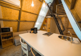 Interieur van safaritent 'A Luxury' bij Trasimeno Glamping Resort, met keuken en slaapzolder.