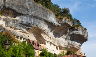 Alojamientos glamping únicos construidos en un acantilado, rodeados de vegetación y bajo un cielo azul.