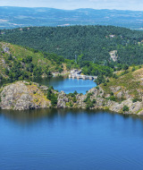 Vista panorámica de un río, colinas verdes y un castillo histórico cerca de Sainte-Sigolène en Auvergne-Rhône-Alpes.
