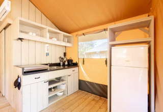 Interior kitchen of Safari tent 'Country' at Papillon Country Resort featuring wooden floor and shelving.