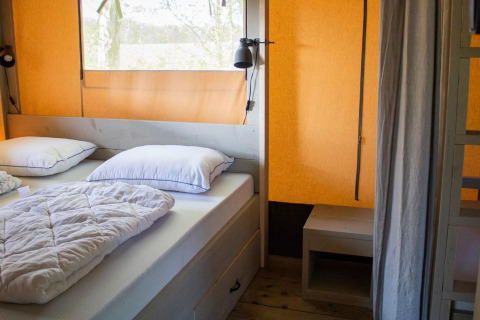 Schlafbereich im Safari-Zelt „Country“ mit Doppelbett, Kissen und Decke im Papillon Country Resort.