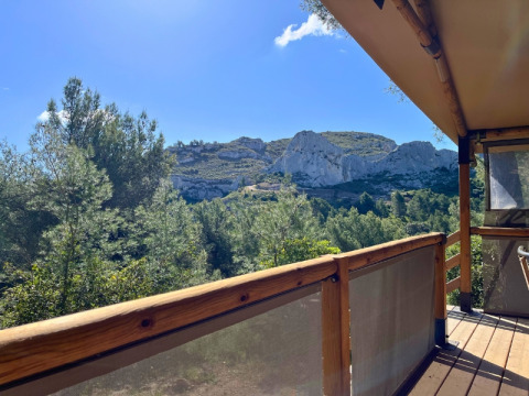 Vista da una terrazza in legno al campeggio La Vallée Heureuse in Provenza-Alpi-Costa Azzurra, Francia, con le montagne.