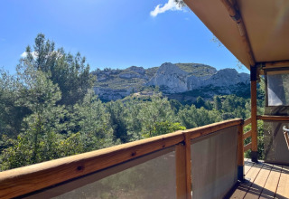 View from a wooden deck at La Vallée Heureuse campsite in Provence-Alpes-Côte d’Azur, France, with scenic hills.