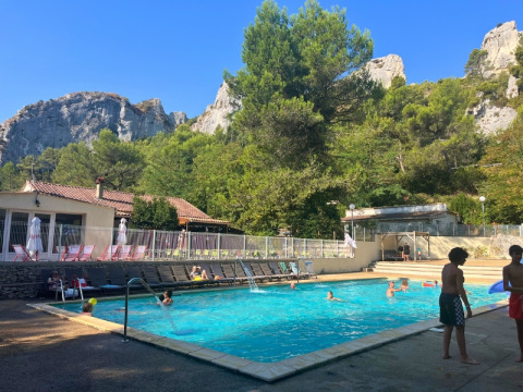 Swimming pool at Campsite La Vallée Heureuse surrounded by mountains and pine trees in Provence, France.