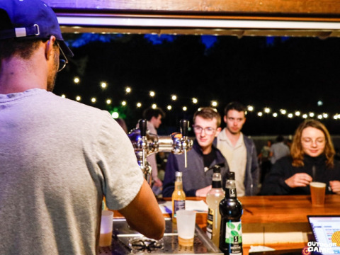 Barista serve bevande agli ospiti al bar all'aperto del Campeggio La Vallée Heureuse in Provenza, Francia.
