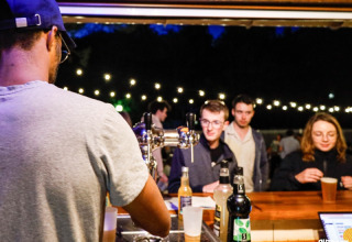 Bartender serving drinks to guests at the outdoor bar at Campsite La Vallée Heureuse in Provence, France.