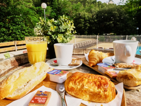 French breakfast with croissants, baguette, orange juice and coffee served outdoors at a campsite in Provence.