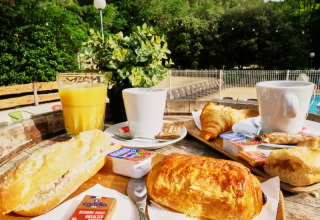 French breakfast with croissants, baguette, orange juice and coffee served outdoors at a campsite in Provence.