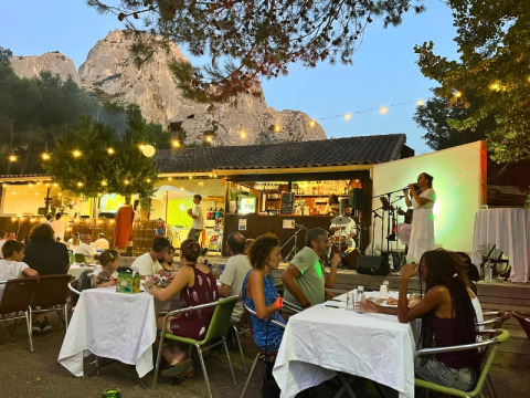 Cena all'aperto con musica dal vivo al campeggio La Vallée Heureuse, tra le montagne della Provenza, Francia.