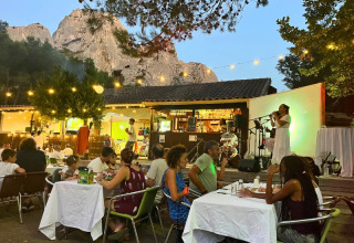 Outdoor dining with live music at Campsite La Vallée Heureuse, set against mountain views in Provence, France.