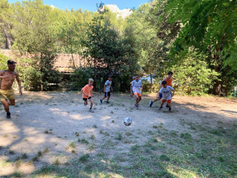 Kids and adults play soccer together on a clearing at La Vallée Heureuse campsite in Provence, France.