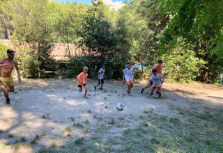 Kids and adults play soccer together on a clearing at La Vallée Heureuse campsite in Provence, France.