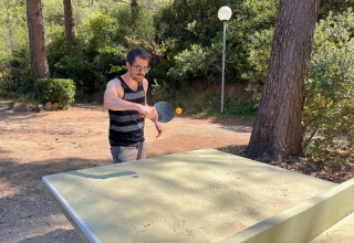 Man playing outdoor table tennis at a campsite, surrounded by trees and nature in Provence-Alpes-Côte d’Azur, France.