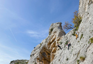 Tre scalatori si arrampicano su una ripida parete rocciosa al campeggio La Vallée Heureuse in Provenza, Francia.