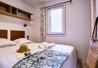 Schlafzimmer im Mobile Home Premium auf Campingplatz La Vallée Heureuse in Frankreich mit Doppelbett.