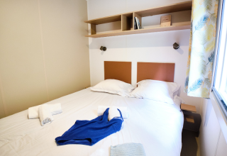 Dormitorio del Mobile Home Premium en el Camping La Vallée Heureuse, Francia, con cama doble y ventana.
