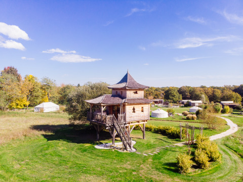 Cabane dans les arbres «Temple perché» au Domaine EcÔtelia, France, entourée de verdure et de ciel bleu.