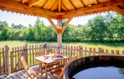 View from Log cabin Temple perché tree house at Domaine EcÔtelia, showing deck seating area and hot tub outdoors.