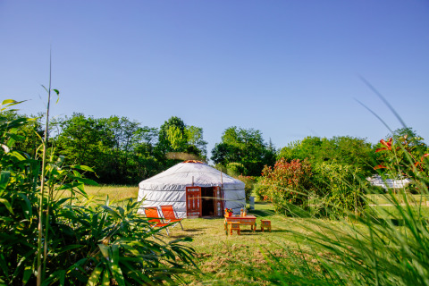 Une yourte traditionnelle au Domaine EcÔtelia en France, entourée de verdure sous un ciel bleu clair.
