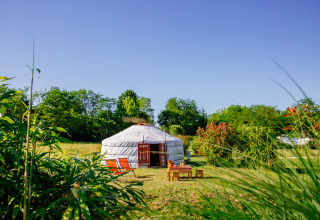Une yourte traditionnelle au Domaine EcÔtelia en France, entourée de verdure sous un ciel bleu clair.