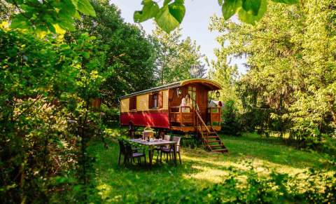 Una colorata roulotte in legno immersa nel verde al parco vacanze Domaine EcÔtelia in Nouvelle-Aquitaine, Francia.