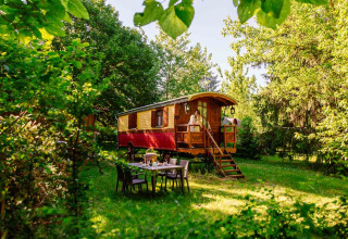 Una colorata roulotte in legno immersa nel verde al parco vacanze Domaine EcÔtelia in Nouvelle-Aquitaine, Francia.