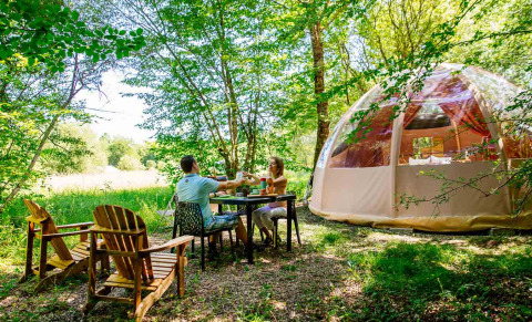 Twee personen aan een tafel bij een dome tent in Domaine EcÔtelia in Nouvelle-Aquitaine, Frankrijk.