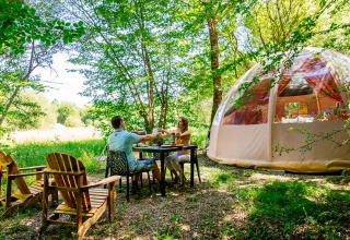Deux personnes à une table près d’un dôme au Domaine EcÔtelia, un parc de vacances en Nouvelle-Aquitaine, France.