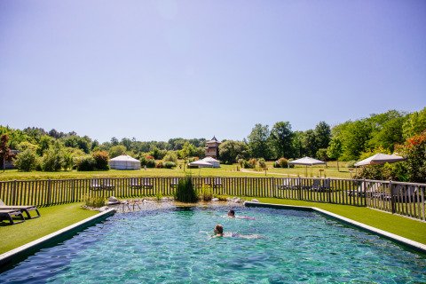 Piscina e persone che nuotano al Domaine EcÔtelia, parco vacanze immerso nel verde della Nouvelle-Aquitaine, Francia.