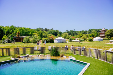 Piscina all'aperto, yurte e visitatori circondati dal verde al Domaine EcÔtelia in Nouvelle-Aquitaine.