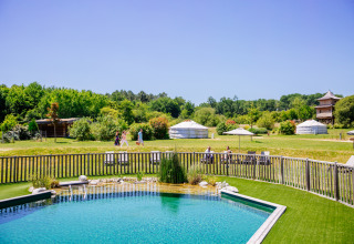 Piscine extérieure, yourtes et visiteurs entourés de verdure au Domaine EcÔtelia en Nouvelle-Aquitaine.