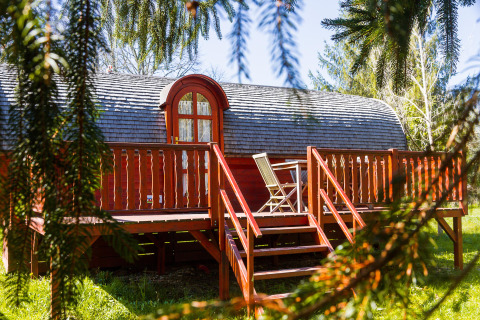 Gypsy wagon Viticole: Gemütliche Holzhütte mit Terrasse und Gartenstühlen in grüner Umgebung.