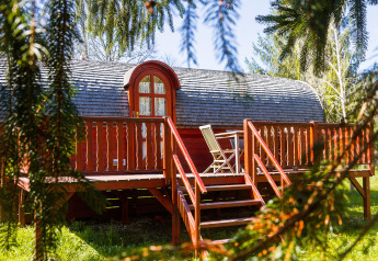 Gypsy wagon Viticole: Gemütliche Holzhütte mit Terrasse und Gartenstühlen in grüner Umgebung.