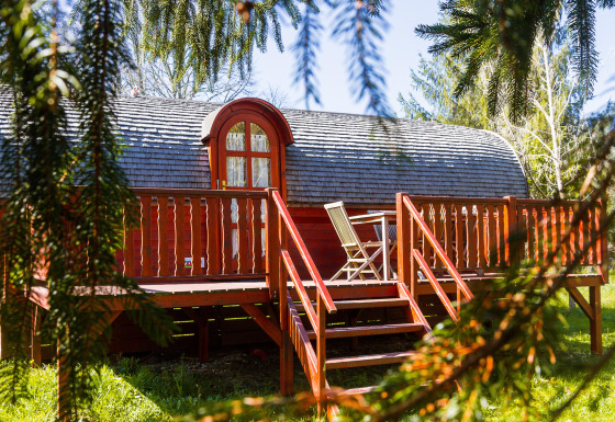 Gypsy wagon Viticole: Gemütliche Holzhütte mit Terrasse und Gartenstühlen in grüner Umgebung.