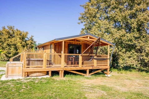 Océania Lodge mit Spa, eine gemütliche Holzhütte mit Terrasse und Hängesessel in grüner Umgebung.