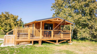 Vista de Océania Lodge con spa, una acogedora cabaña de madera con terraza, hamaca y jacuzzi exterior.