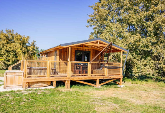 Océania Lodge mit Spa, eine gemütliche Holzhütte mit Terrasse und Hängesessel in grüner Umgebung.