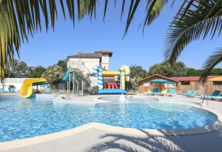 Swimming pool with water slides and loungers surrounded by palm trees at Ushuaïa Villages Le Parc de la Grève, France.