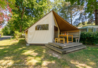 Tente safari Ecolodge avec terrasse en bois et coin repas extérieur, située dans un camping arboré.