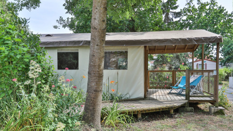 De Sahari Ecotent Mindervaliden safaritent met houten terras, stoelen en omgeven door planten.