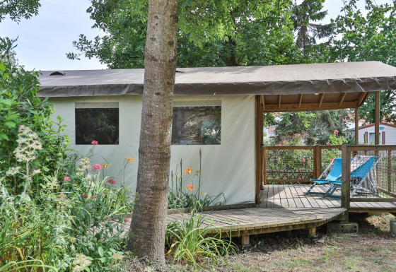 De Sahari Ecotent Mindervaliden safaritent met houten terras, stoelen en omgeven door planten.