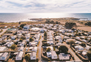 Luchtfoto van Flower Camping La Pointe du Talud met vakantiewoningen aan de kust in Bretagne, Frankrijk.