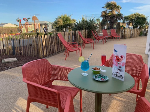 Terraza al aire libre con sillas rojas y cócteles en Flower Camping La Pointe du Talud, Bretaña, Francia.