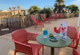 Buitenterras met rode stoelen en cocktails bij Flower Camping La Pointe du Talud in Bretagne, Frankrijk.