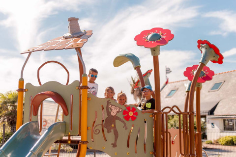 Children playing on a colorful playground on a sunny day at Flower Camping La Pointe du Talud in Brittany, France.