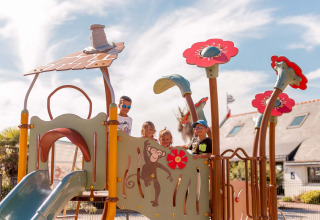 Kinderen spelen op een kleurrijke speeltuin bij Flower Camping La Pointe du Talud in Bretagne, Frankrijk.