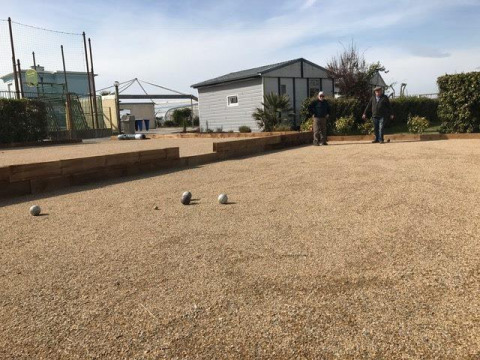 Twee personen spelen pétanque op een kiezelveld bij Flower Camping La Pointe du Talud in Bretagne, Frankrijk.