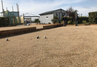 Two people play pétanque on a gravel court at Flower Camping La Pointe du Talud in Brittany, France.
