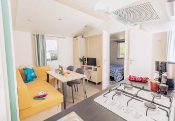 Luminoso y moderno Mobil home Comfort BAHIA con cocina, comedor, sofá y vista al dormitorio.