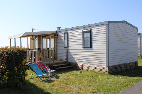 Vista exterior de la Mobile home Premium HORIZON con terraza cubierta y tumbonas bajo el sol.